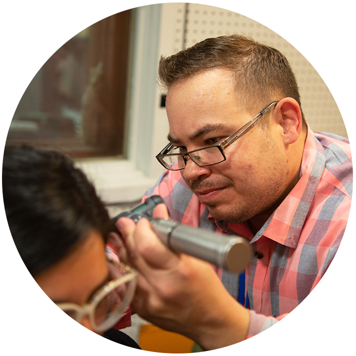 Student conducting ear exam using device