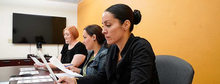 Students sitting a conference room table looking at documents