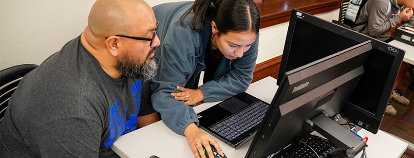 Two students looks at laptop together in class