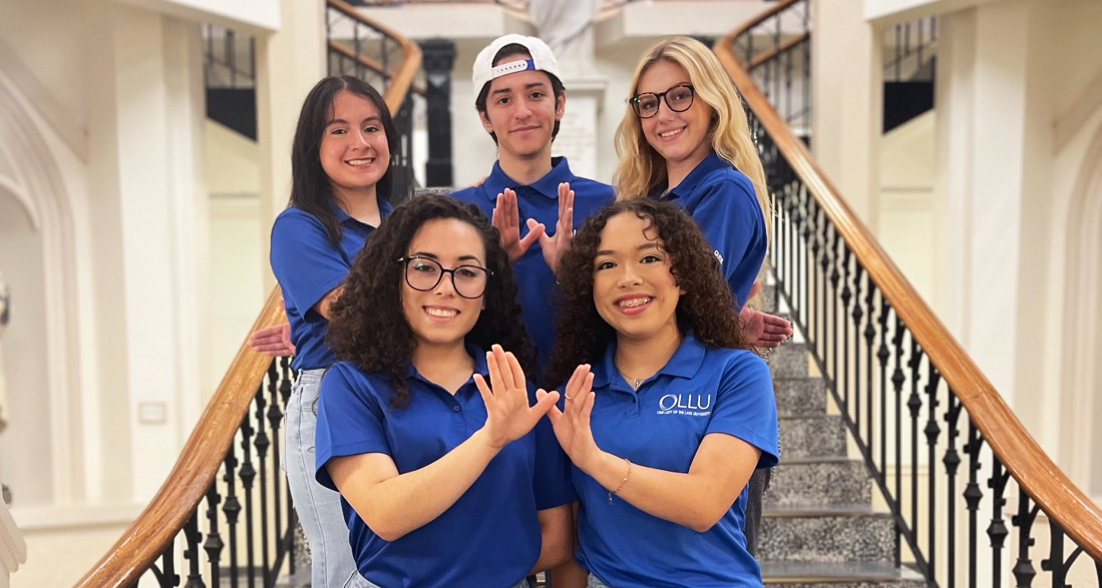 Group of students on staris showing wings up